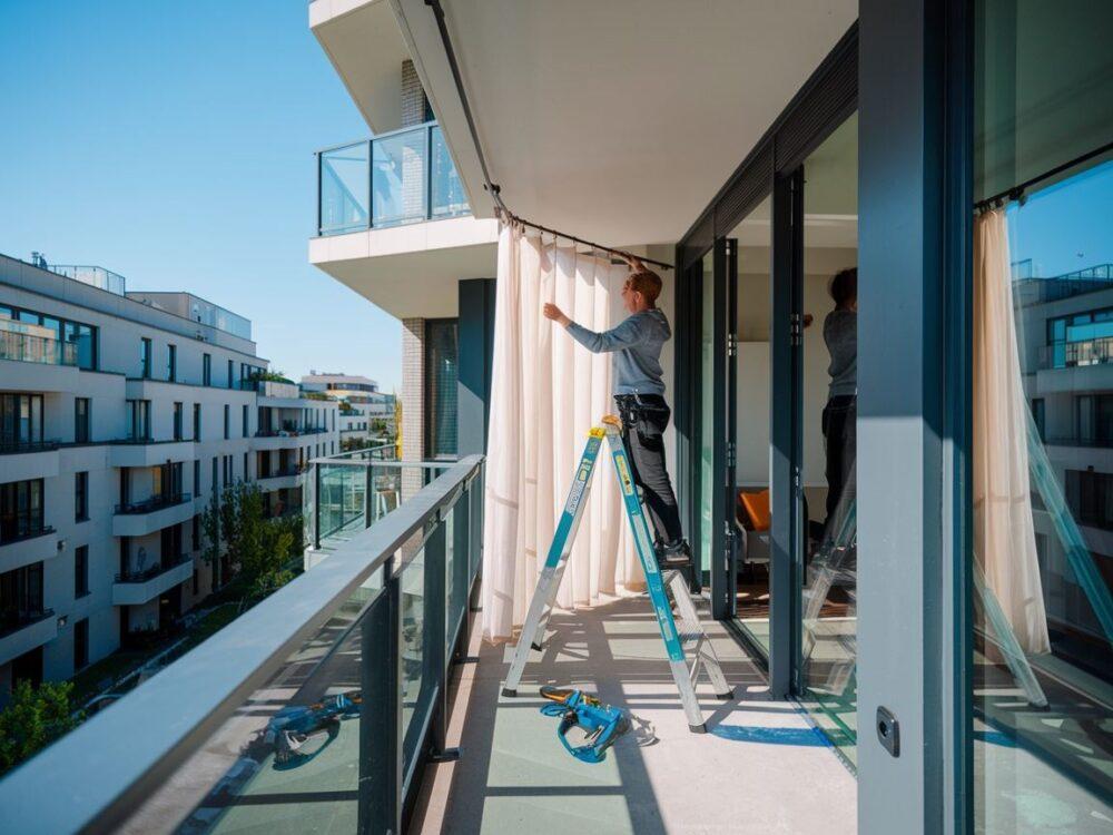 osoba wiesza zasłony balkon